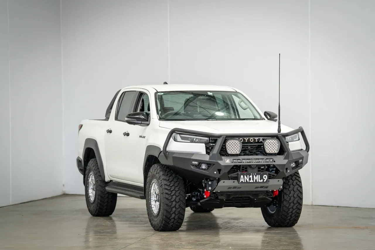 White pickup truck with off-road modifications in a studio showroom, front three-quarter view — Ol Mate 4x4 in Tuggerah, NSW