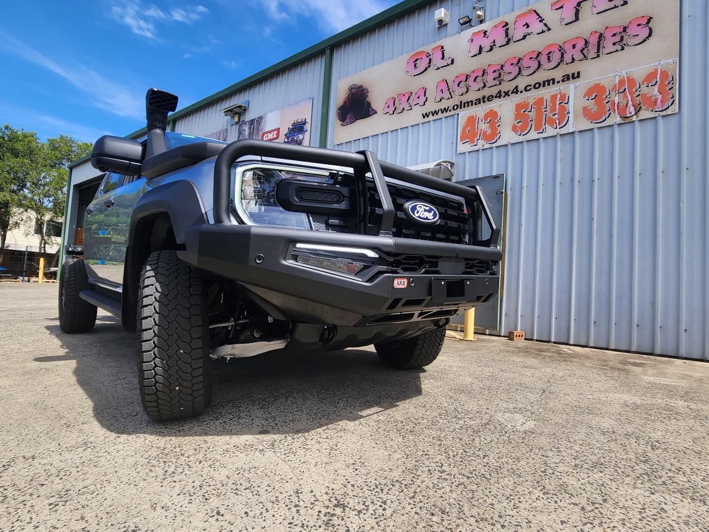 Black off-road truck parked outside a building with a large sign under a blue sky — Ol Mate 4x4 in Tuggerah, NSW
