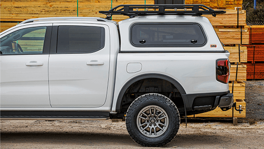 White pickup truck with canopy and roof rack parked beside stacked lumber in an industrial yard — Ol Mate 4x4 in Tuggerah, NSW