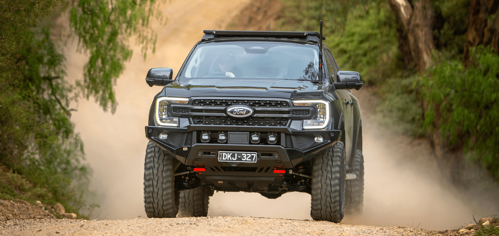 Black off-road Ford SUV driving on a dusty dirt road between green bushes — Ol Mate 4x4 in Tuggerah, NSW