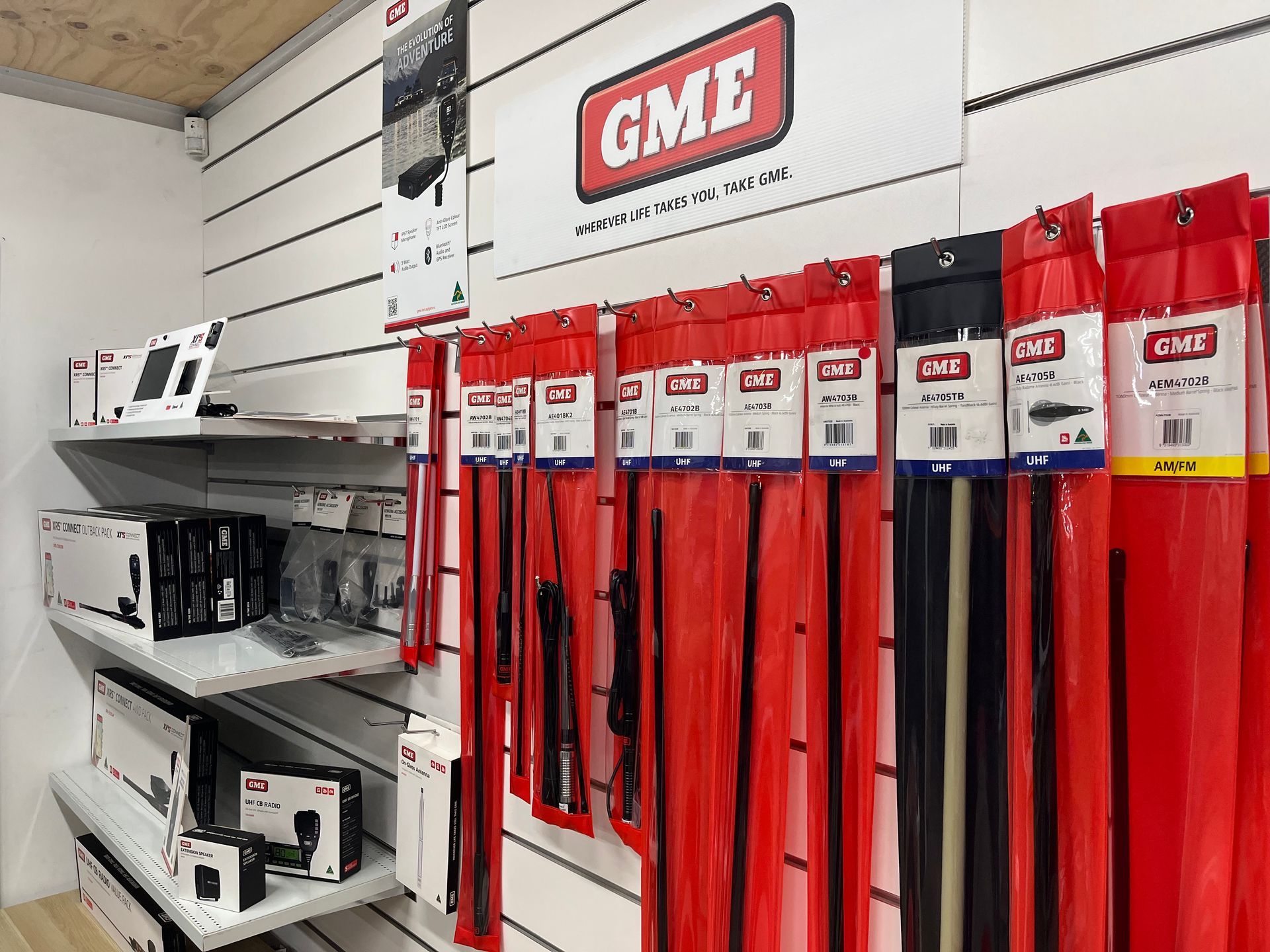 GME store display with fishing rods and tackle boxes on white shelving against a wall sign — Ol Mate 4x4 in Tuggerah, NSW