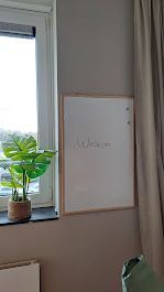 Een whiteboard op een grijze muur met het woord