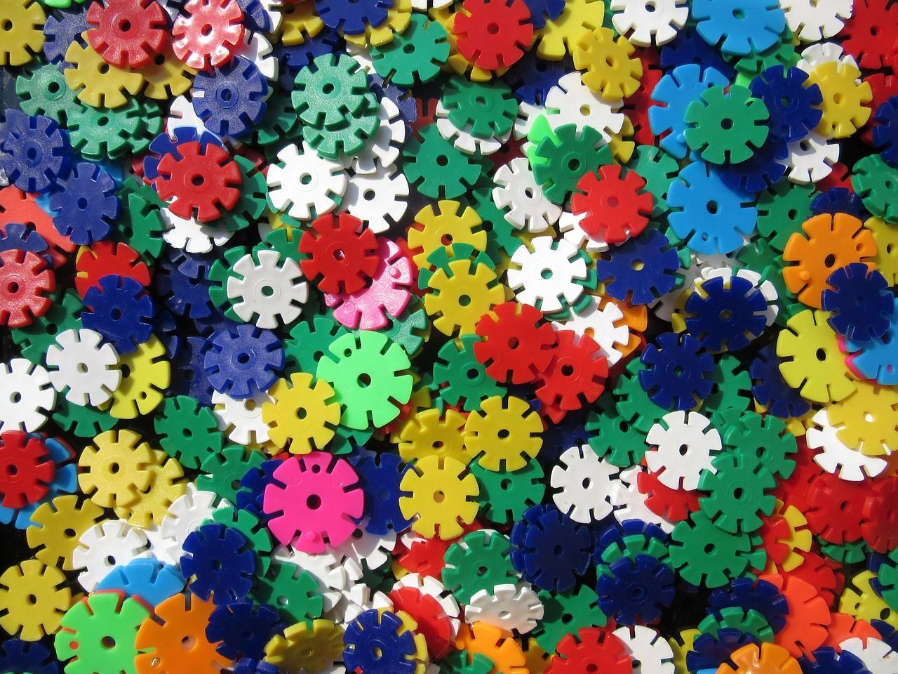 Een stapel felgekleurde, ronde, in elkaar grijpende speelgoedstukjes: rood, blauw, groen, geel, oranje en wit.
