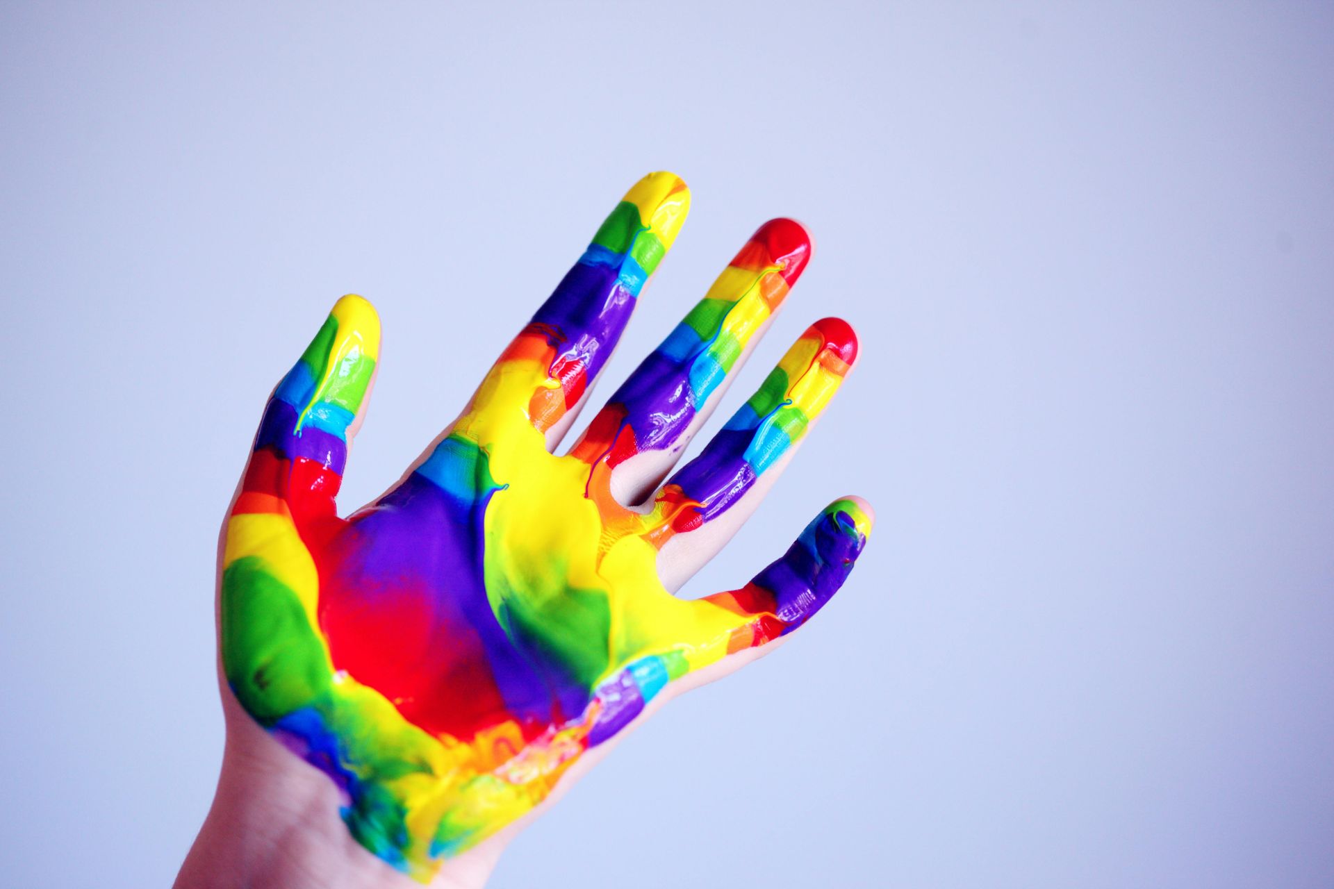 Hand, met de handpalm naar boven, bedekt met regenboogverf.