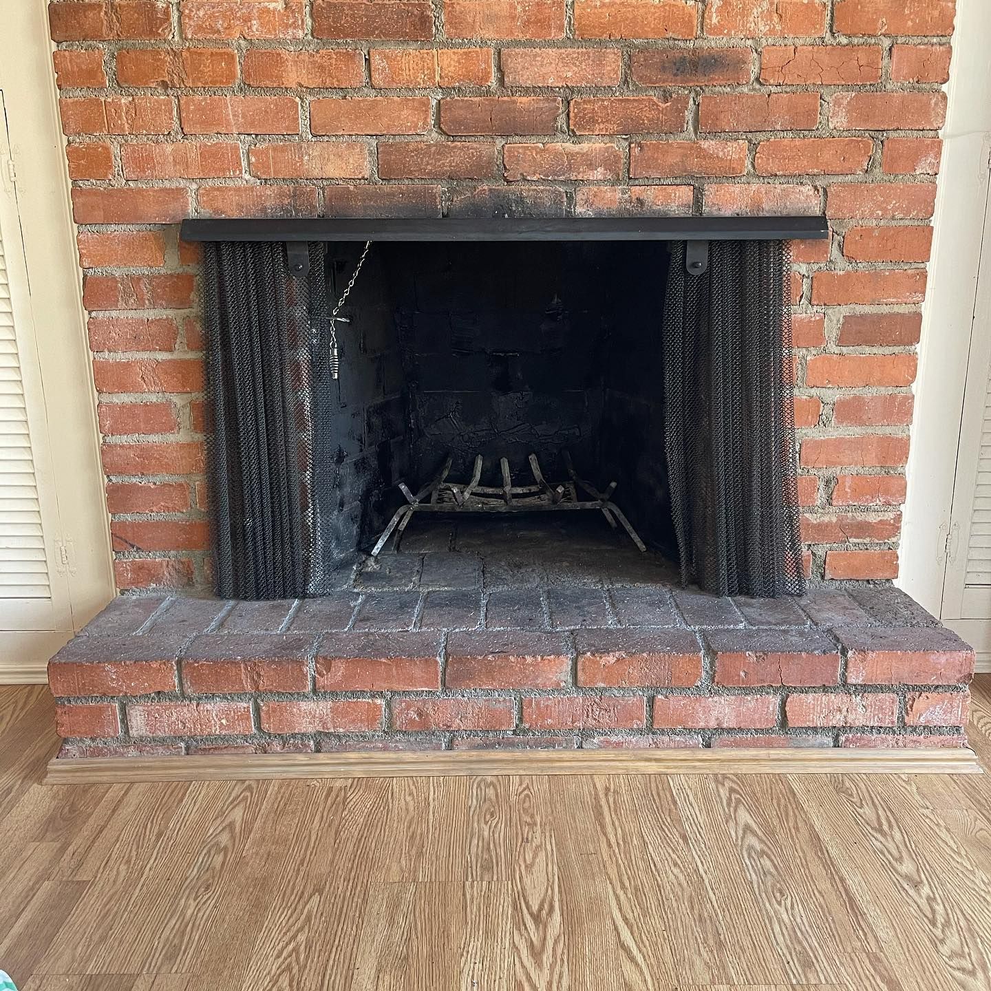 Brick fireplace with metal grate and screen.