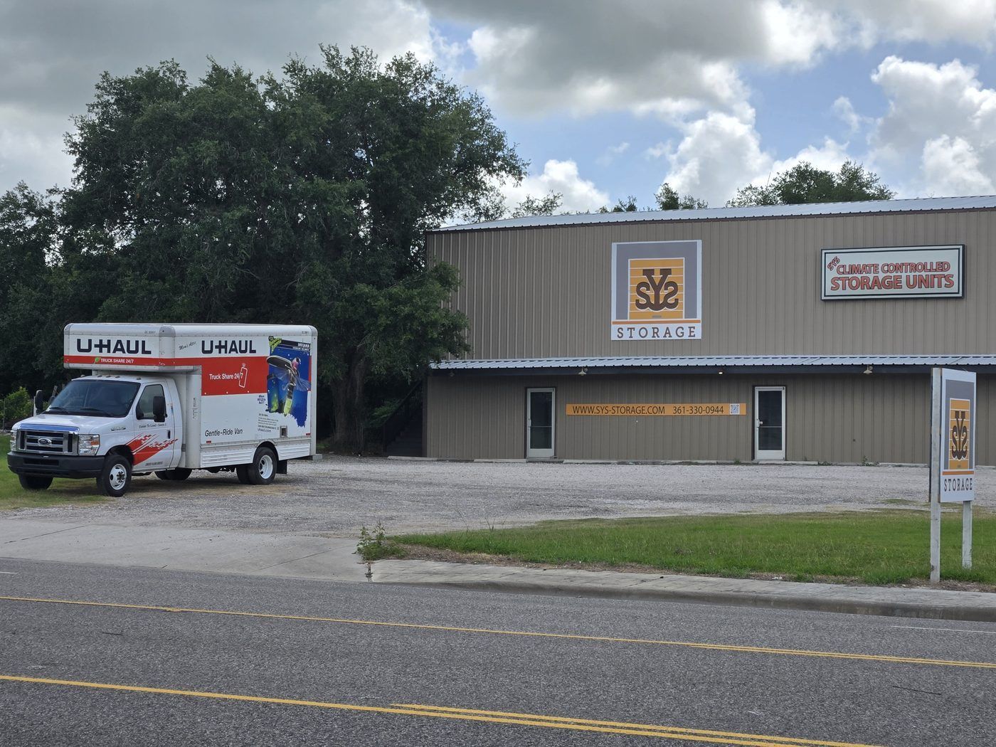 U-Haul truck parked outside a storage facility building with signage and loading doors