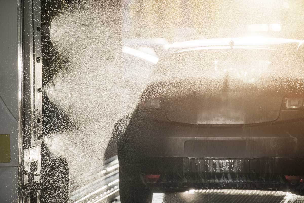 Vehicle Going Through Touch Free Automatic Express Car Wash Being Sprayed Cleaned And Rinsed.