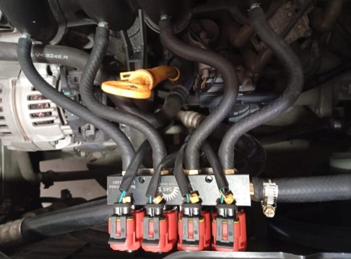 Compartimento del motor de un automóvil con varilla de nivel de aceite naranja y cinco bobinas