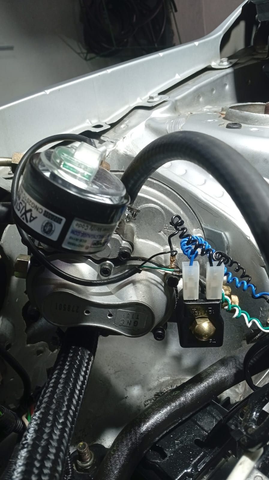 Primer plano de un pequeño conjunto mecánico con cableado, mangueras y un motor circular