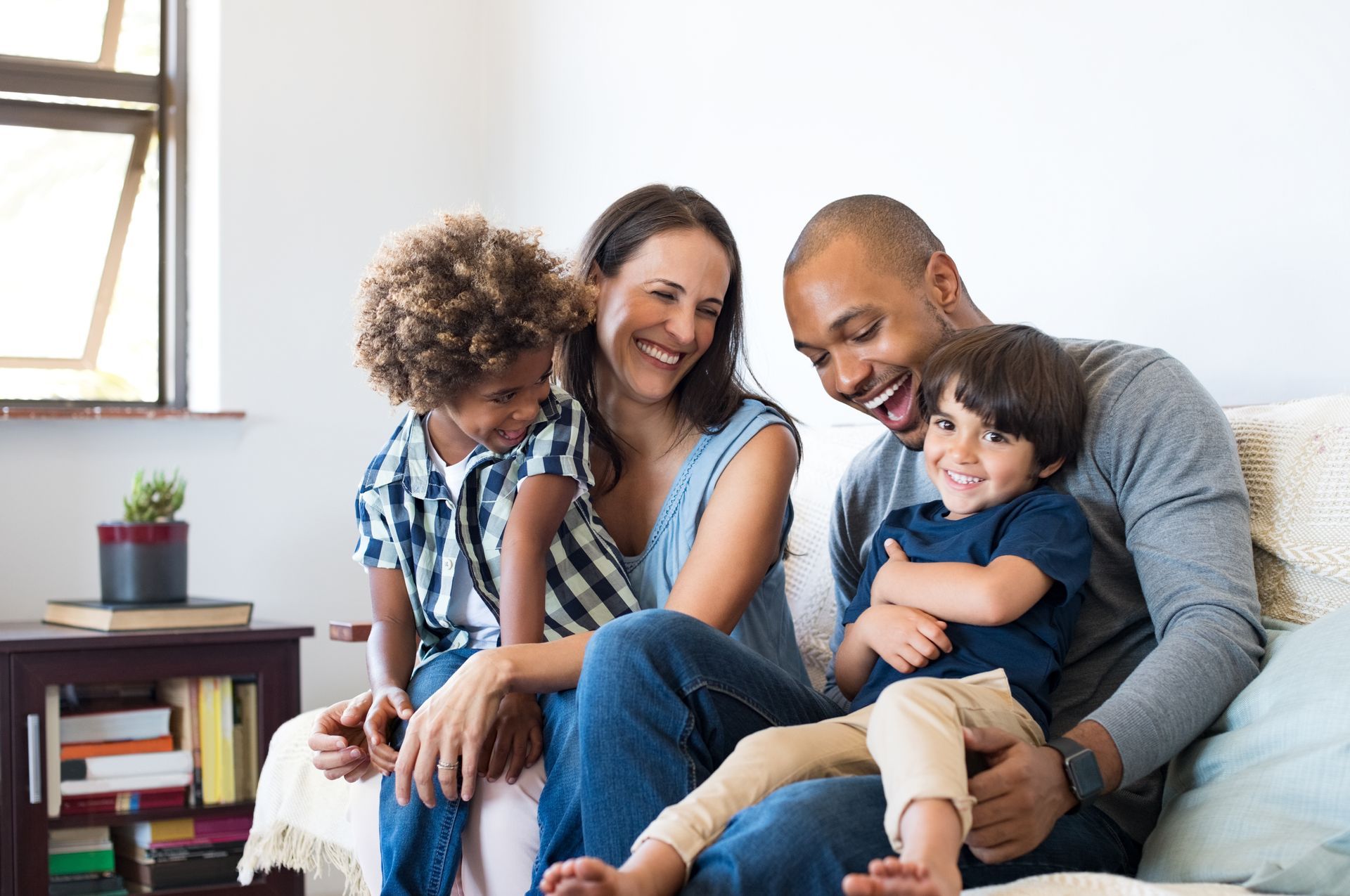 A family is sitting on a couch together and smiling.