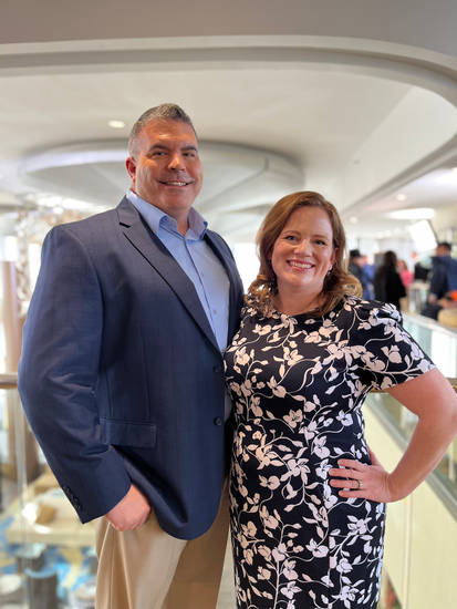 A man in a suit and a woman in a dress are posing for a picture.