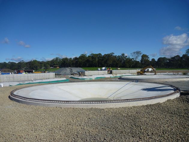 A large circular concrete structure is being built on a dirt field.