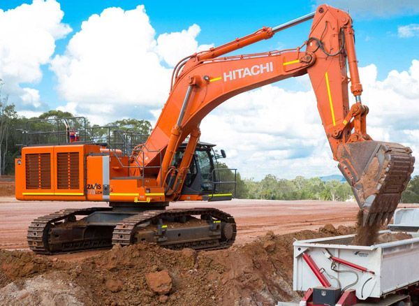 A hitachi excavator is loading dirt into a dump truck