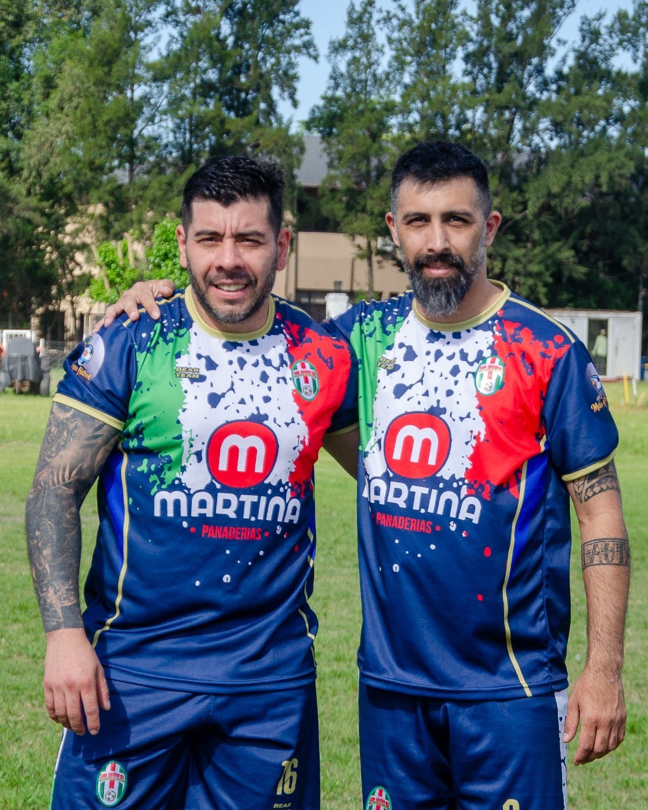 Dos hombres de pie uno al lado del otro con camisetas estampadas a juego en azul marino, rojo, verde y blanco