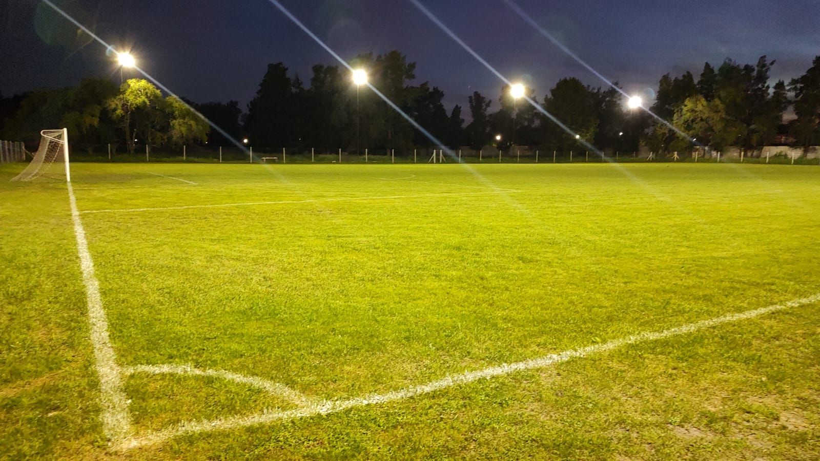 Un campo de fútbol al aire libre iluminado por brillantes luces de estadio durante la noche