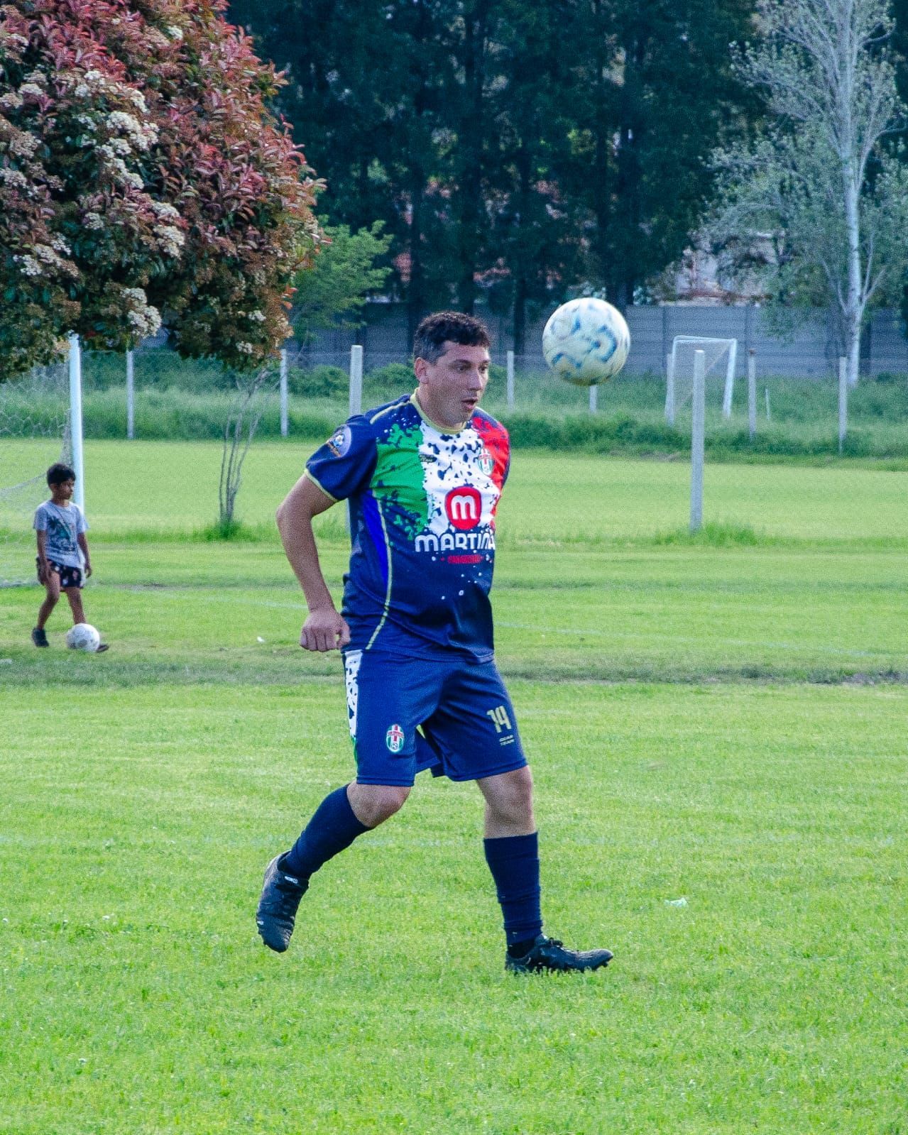 Un jugador de fútbol con una camiseta azul con el estampado de la bandera italiana mira hacia arriba