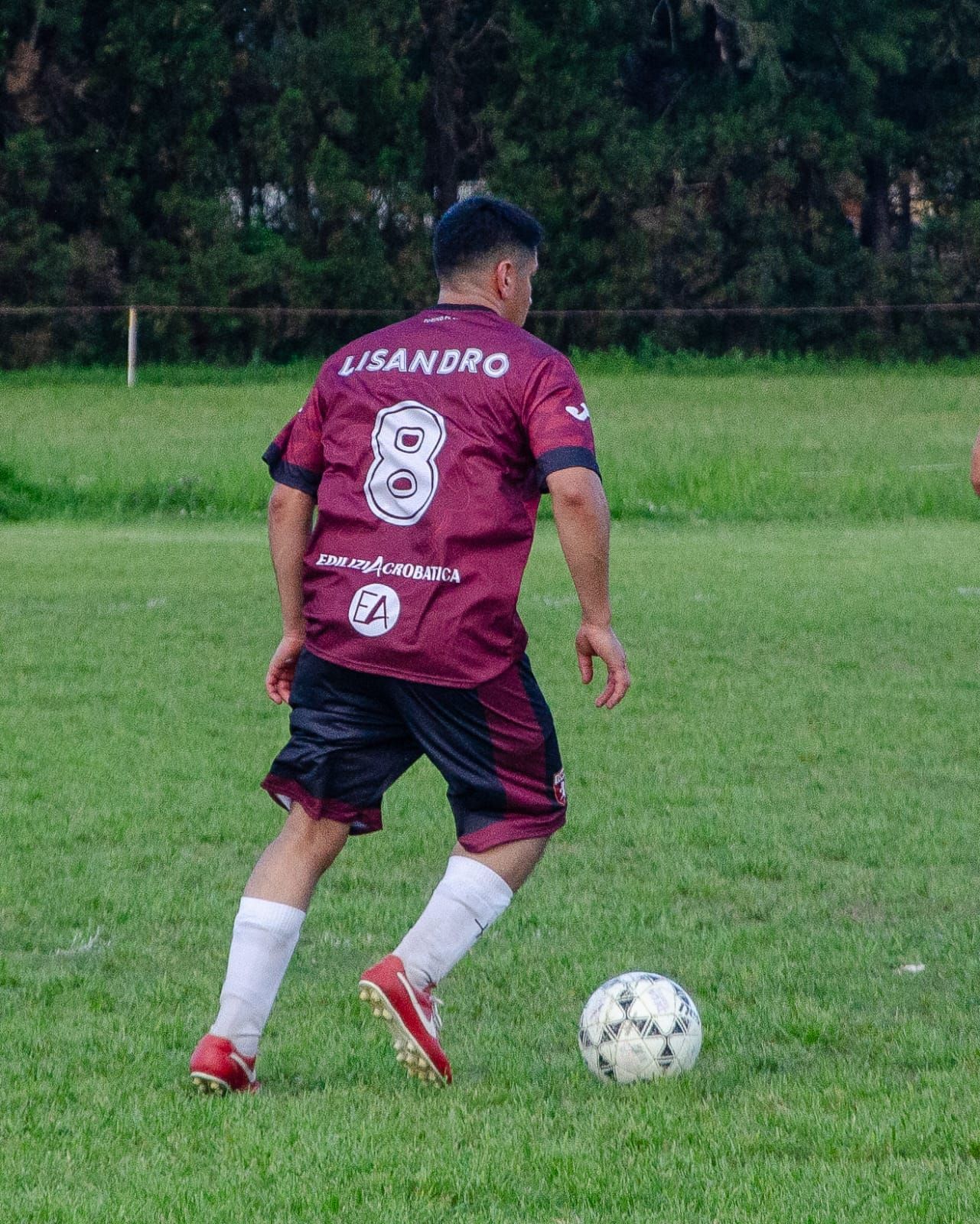 Un jugador de fútbol con una camiseta granate con el nombre 