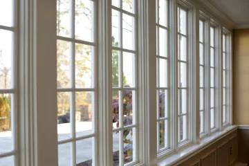 A row of white-framed windows with multiple panes overlooking a blurry outdoor area.