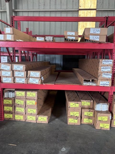 Warehouse shelves stacked with cardboard boxes, some labeled, in a red metal rack.