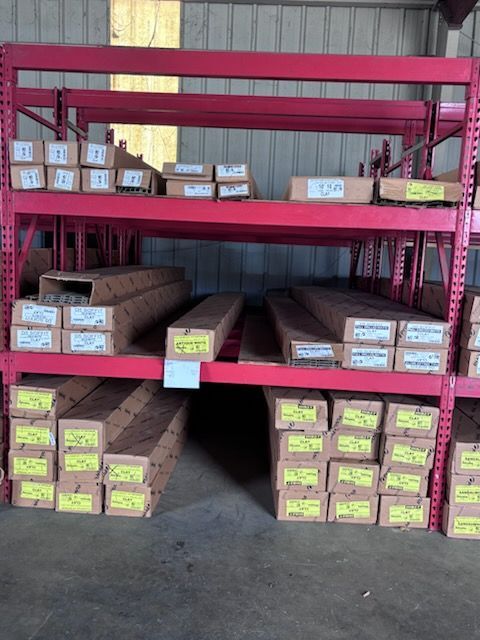 Metal shelving unit filled with labeled boxes and lumber in a warehouse or storage area