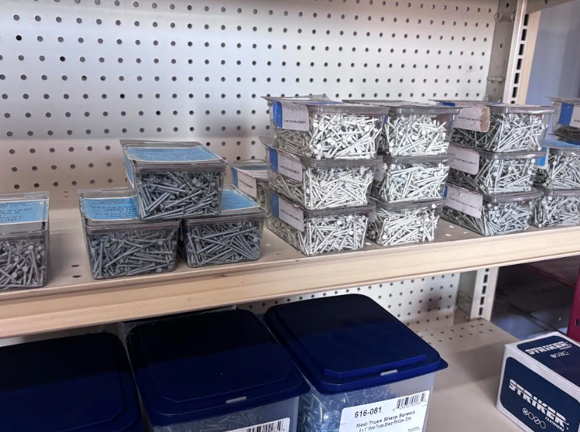 Shelves of assorted stacked metal screws and bolts in clear and blue bins at a hardware store