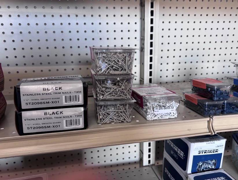 Shelves of stacked small storage boxes and packaged items in a store aisle against a pegboard wall
