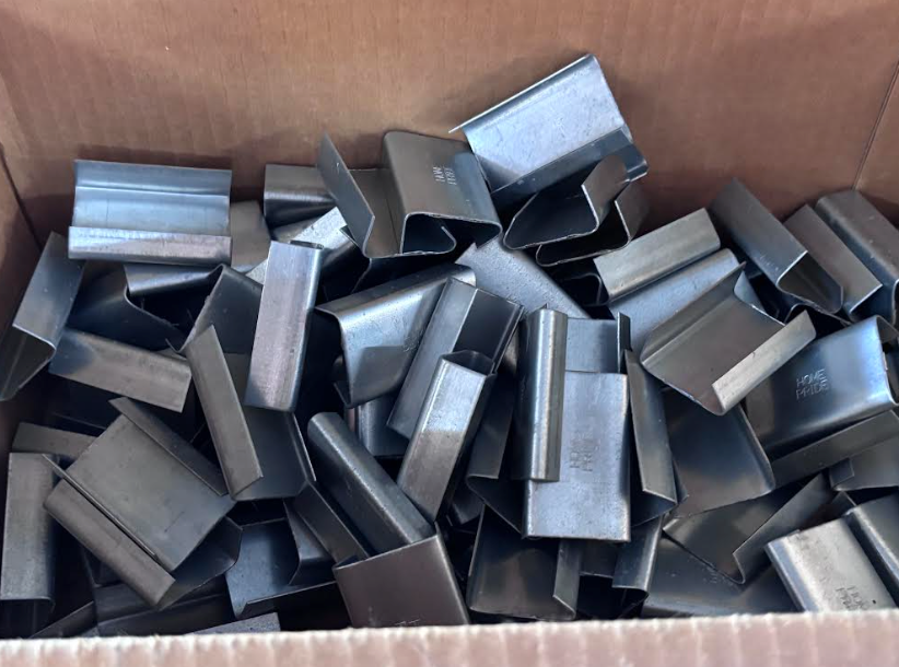 Box of scattered gray metal rectangular pieces stacked in a cardboard container