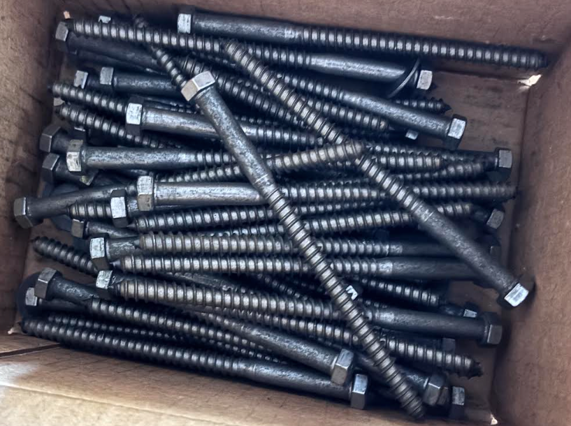 Box filled with stacked black-and-silver threaded metal rods