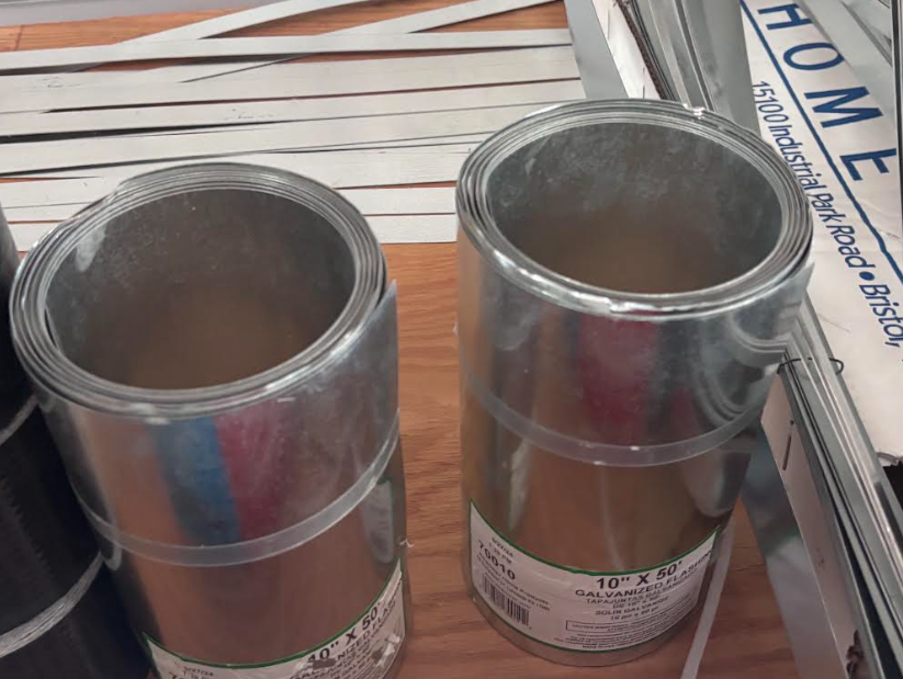 Two shiny metal duct pipe sections standing upright on a store shelf.