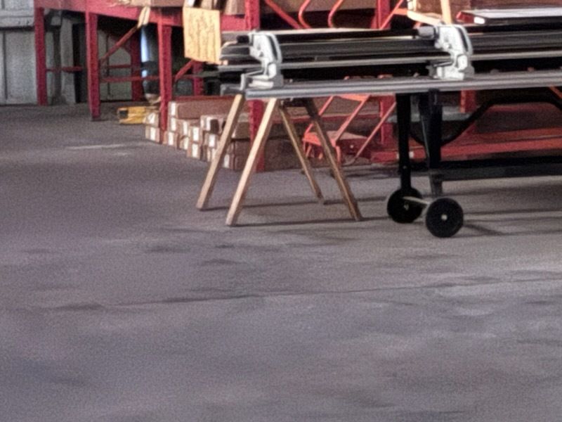Foldable cart with black wheels on a concrete floor in an industrial warehouse setting