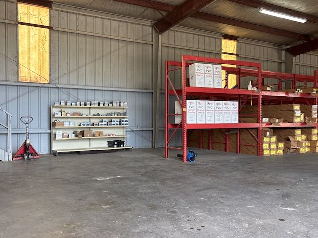 Empty warehouse interior with metal shelves, storage boxes, and a concrete floor