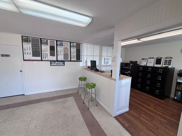 Lobby with beige carpet, white walls, a counter with stools, and black mail lockers on wood flooring.
