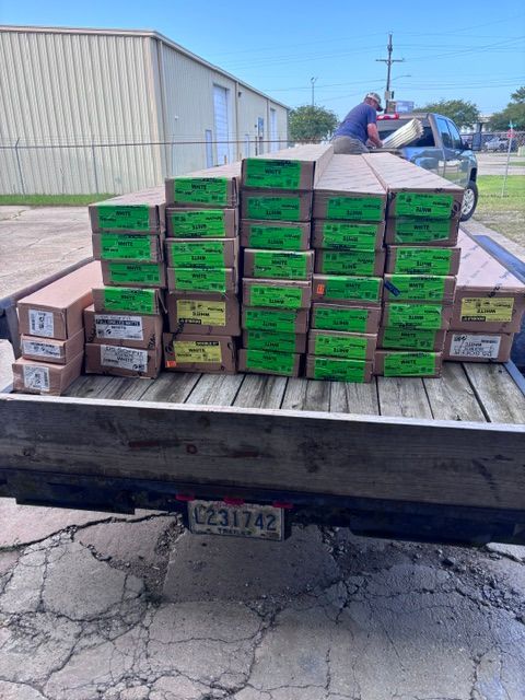 Flatbed trailer loaded with stacked brown and green boxed goods in an industrial lot