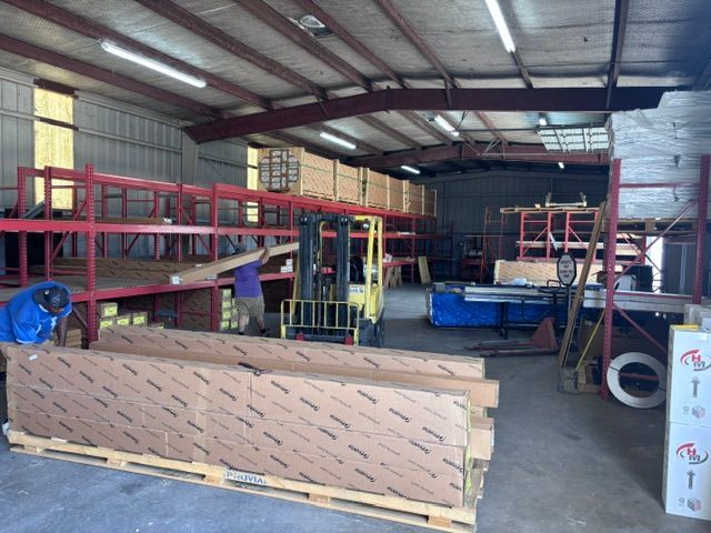 Warehouse interior with red metal shelving, stacked materials, and equipment on a concrete floor