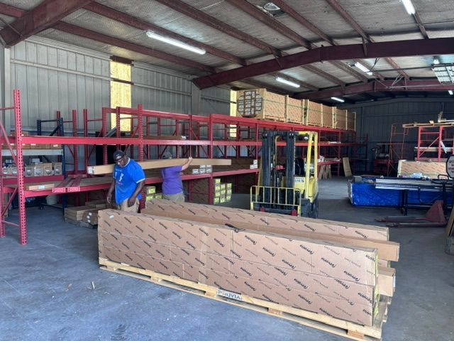 Warehouse interior with red racks, a worker in blue, and a large wrapped pallet in the foreground