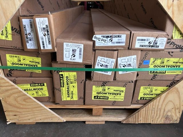 Wooden crate filled with small labeled boxes and bright yellow tags, secured with green straps.