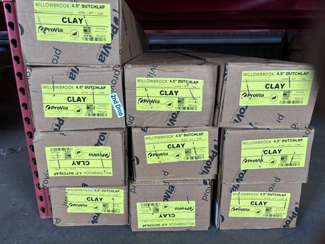 Stacked cardboard boxes labeled “CLAY” in a storage area