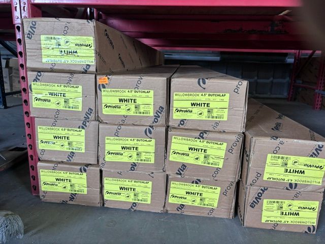 Boxed packages stacked on metal shelving in a storage area, with yellow labels and a red shelf frame.