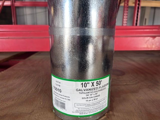 Galvanized metal pipe labeled “10” x 50” on a warehouse floor with red shelving behind it