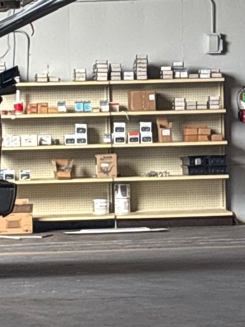 Shelves stocked with boxes and supplies against a gray wall in an industrial storage area