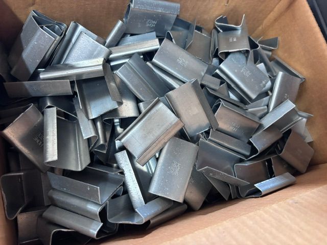 Cardboard box filled with small silver metal clips or brackets