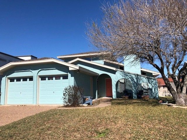 a blue house with a red door and a tree in front of it | Corpus Christi, TX | GT Roofing
