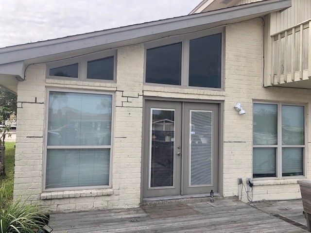 a white house with a lot of windows and a sliding glass door . | Corpus Christi, TX | GT Roofing