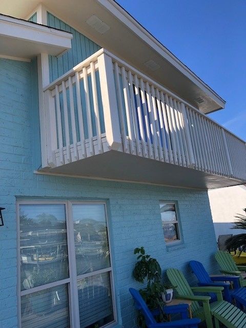 a blue house with a balcony and blue chairs | Corpus Christi, TX | GT Roofing
