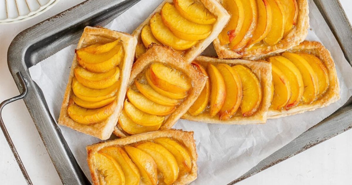 A tray filled with peach tarts on a table.