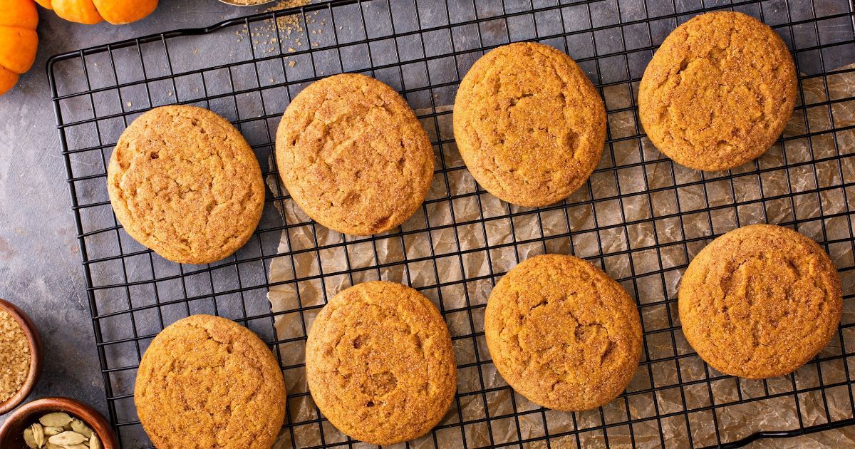 A bunch of pumpkin cookies are sitting on a cooling rack.