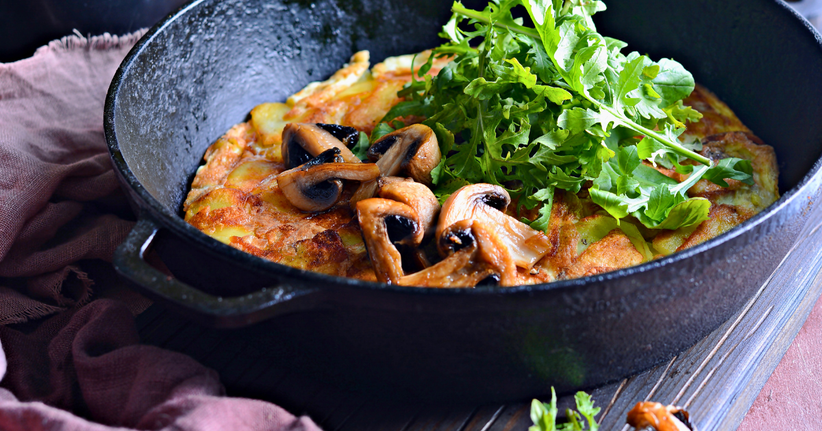 A pan with Arugula  and Mushroom Frittata on a table.