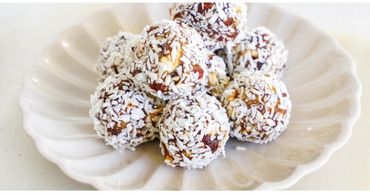 A white plate topped with a bunch of balls covered in coconut.