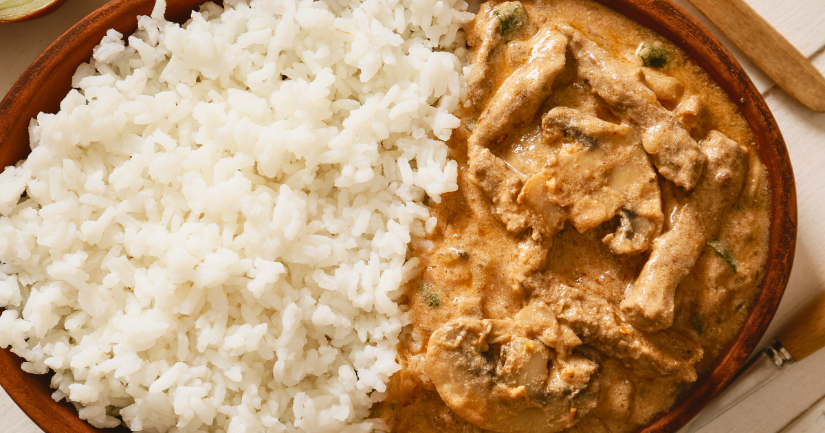 A bowl of rice and chicken Stroganoff on a table.