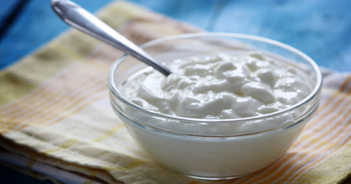 There is a bowl of sour cream with a spoon in it.